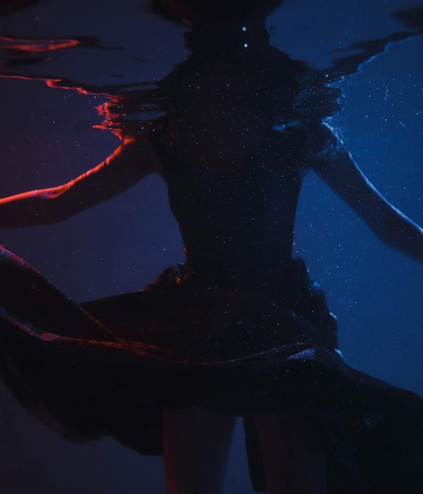 Woman in a graceful flowing motion against a dark background.